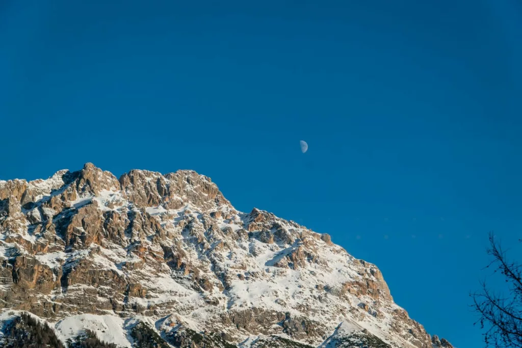Der Mond stand hoch über den Bergen, die von der Sonne angestrahlt wurden.