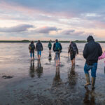 Foto einer Gruppe bei Sonnenuntergang während der Wattwanderung bei Dagebüll
