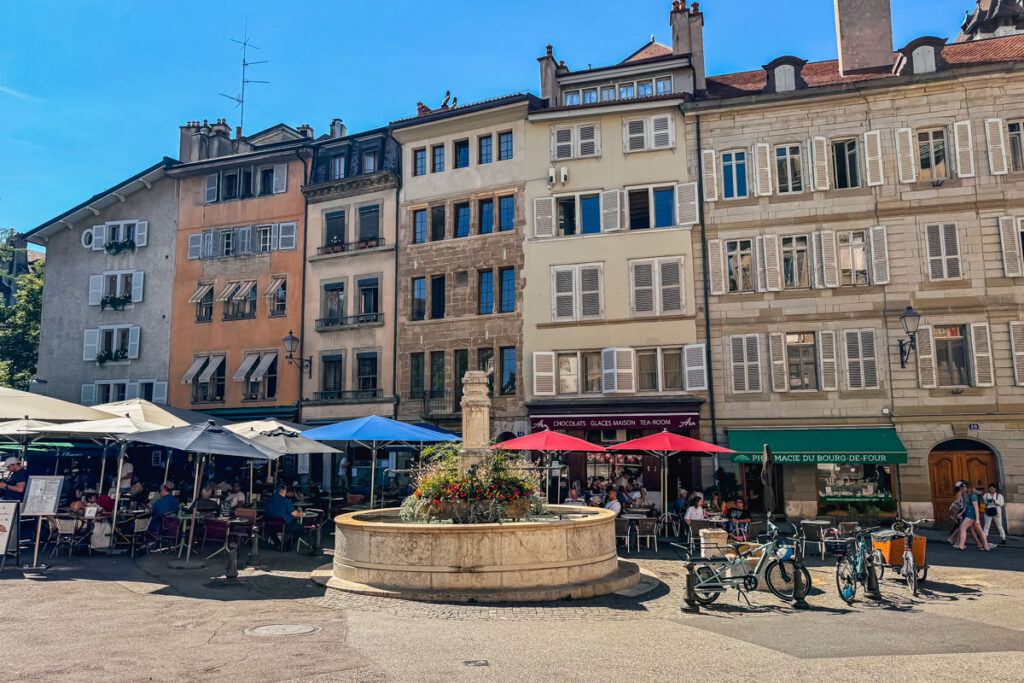 Eine kostenlose Sehenswürdigkeit für ein Tag in Genf ist der Place du Bourg-de-Four mit Cafés, Sonnenschirmen, Brunnen und Antiquitätenläden.