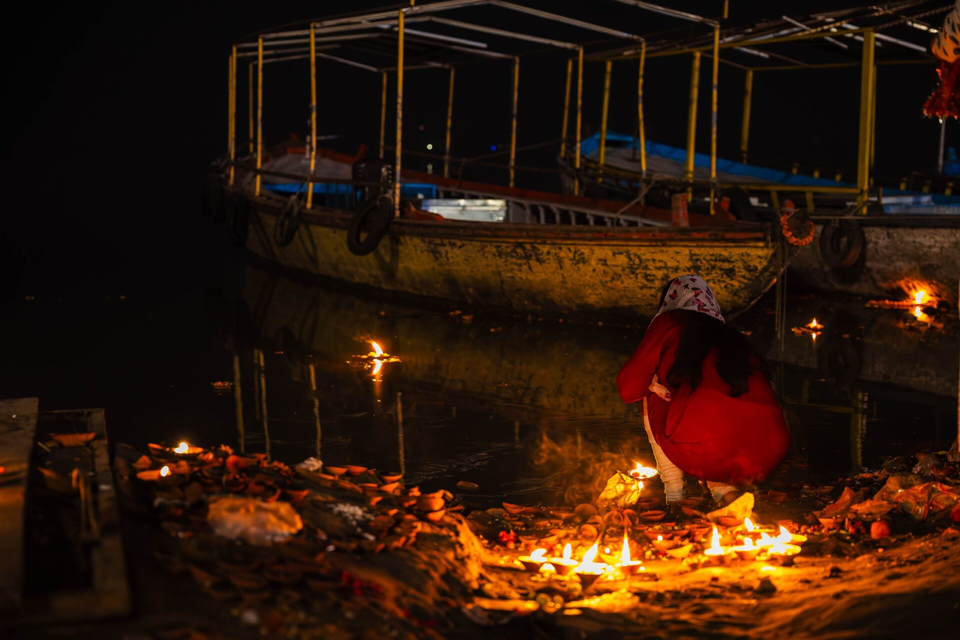 Frau am Ganges legt Kerzen für Diwali ins Wasser