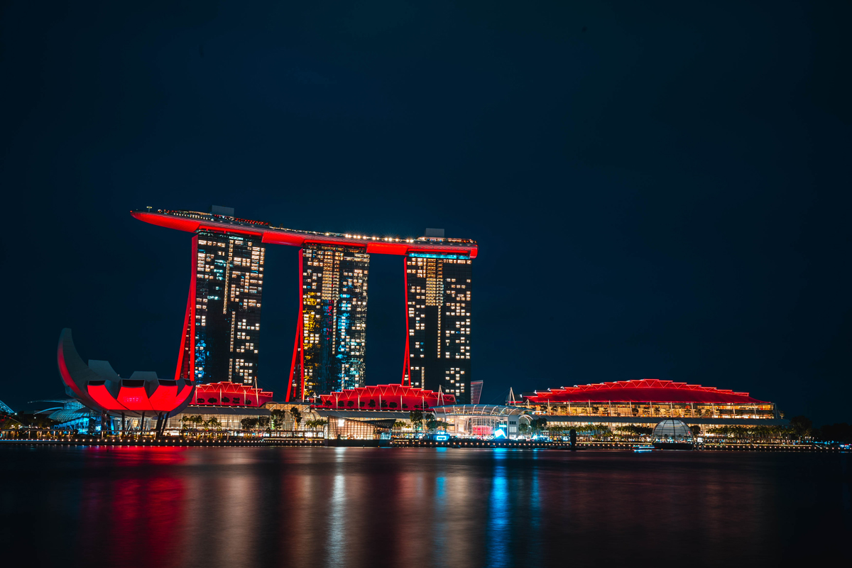 Aufnahme bei Nacht von dem rot angestrahlten Marina Bay Sands Hotel in Singapur, mit seinen drei Türmen.
